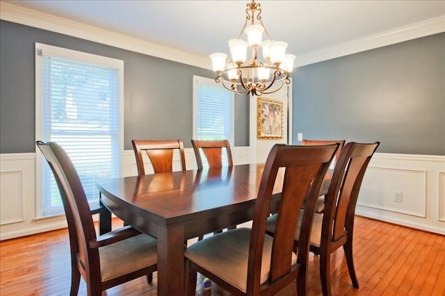 dining area featuring crown molding, light wood-style flooring, and wainscoting