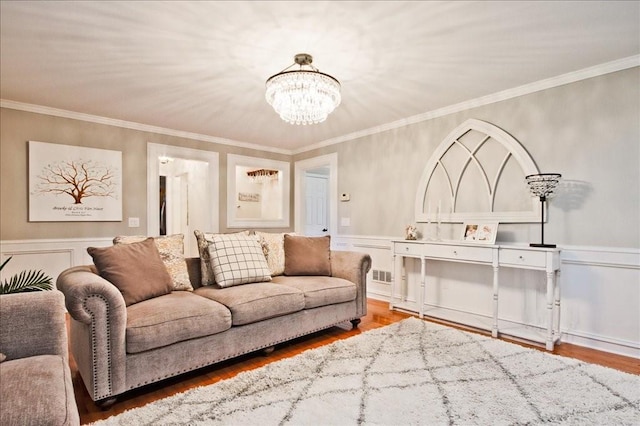 living area with a chandelier, crown molding, and wood finished floors