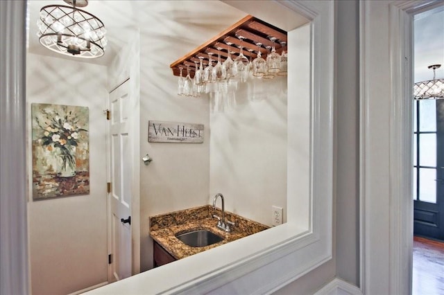 interior space with wet bar, a chandelier, and a sink