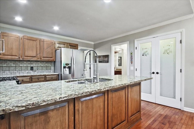 kitchen with brown cabinetry, a sink, french doors, stainless steel refrigerator with ice dispenser, and tasteful backsplash