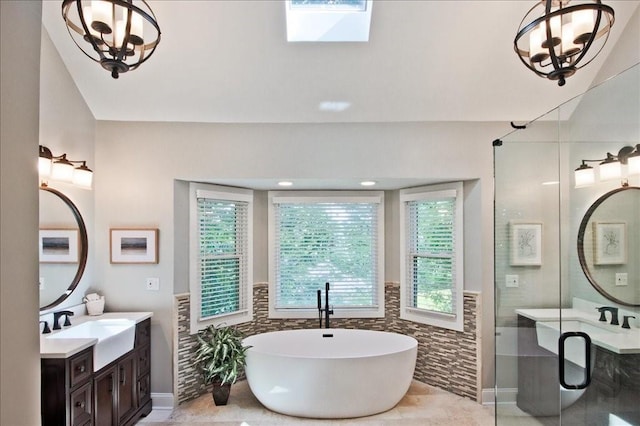 full bathroom featuring an inviting chandelier, a freestanding tub, two vanities, a sink, and tile walls