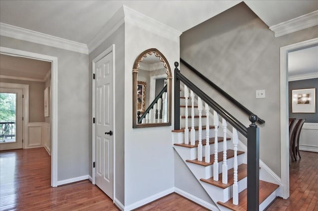 staircase with wood finished floors and crown molding