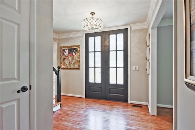 foyer entrance featuring visible vents, french doors, light wood-style floors, and ornamental molding