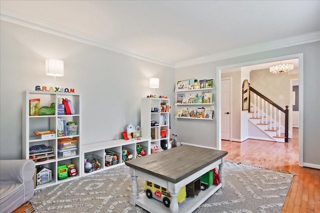 recreation room with ornamental molding, baseboards, and wood finished floors