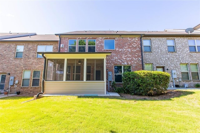rear view of property featuring a yard, a sunroom, and brick siding