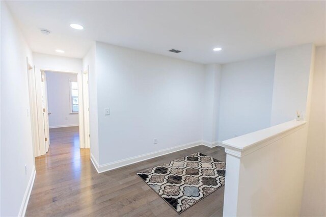 hall featuring wood finished floors, recessed lighting, baseboards, and an upstairs landing