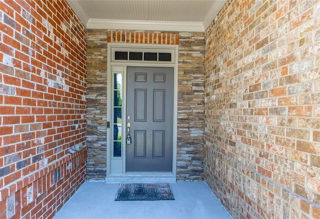 entrance to property featuring a porch, stone siding, and brick siding