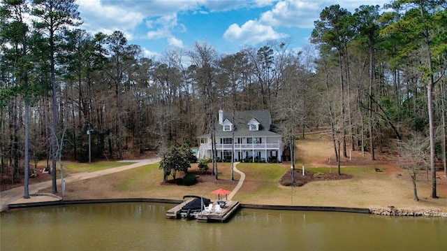 back of property with a water view and a lawn