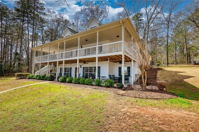 back of property with stairway, a lawn, a chimney, and a ceiling fan