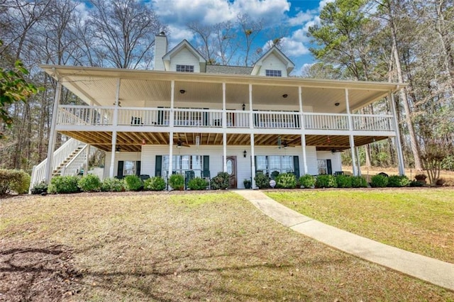 rear view of property featuring stairway, a chimney, and a yard