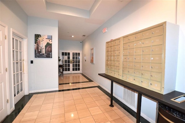 corridor featuring a mail area, light tile patterned flooring, and french doors