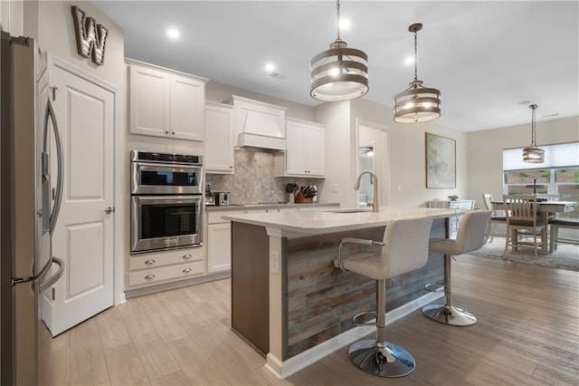 kitchen with pendant lighting, light hardwood / wood-style floors, appliances with stainless steel finishes, and sink