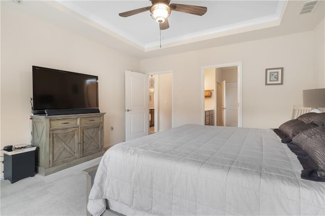 carpeted bedroom with ceiling fan, a tray ceiling, and ensuite bathroom