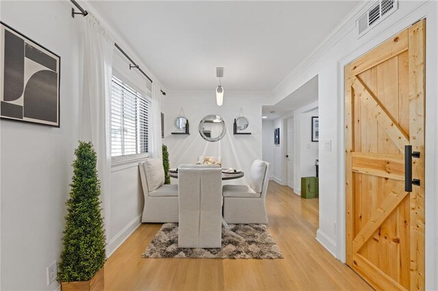 10 26th St NW Unit A2, Atlanta, GA 30309 - dining space with a barn door, baseboards, visible vents, wood finished floors, and ornamental molding