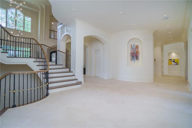 stairs featuring an inviting chandelier and crown molding