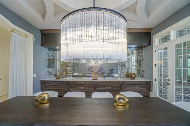 interior space with a raised ceiling, dark brown cabinets, and french doors