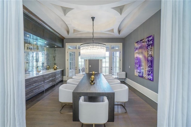 dining area featuring dark hardwood / wood-style floors, coffered ceiling, a notable chandelier, and a tray ceiling