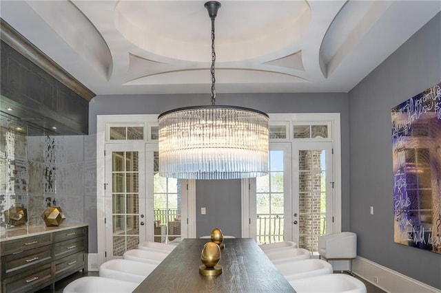 dining room featuring a notable chandelier, a tray ceiling, and french doors