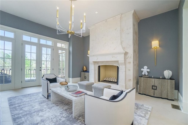 living room with an inviting chandelier, a high end fireplace, light tile floors, and french doors