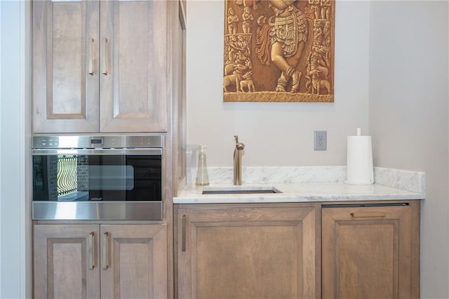 kitchen with sink, light stone countertops, and oven