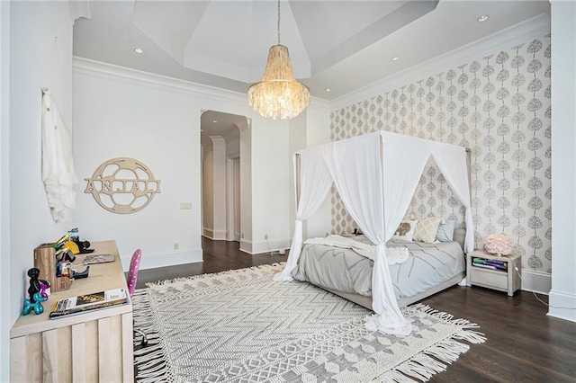 bedroom featuring an inviting chandelier, a tray ceiling, dark wood-type flooring, and ornamental molding