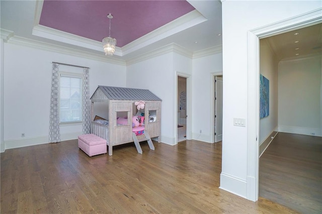 bedroom featuring an inviting chandelier, crown molding, dark wood-type flooring, and a raised ceiling