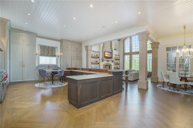 kitchen featuring decorative light fixtures, a notable chandelier, parquet flooring, and ornate columns