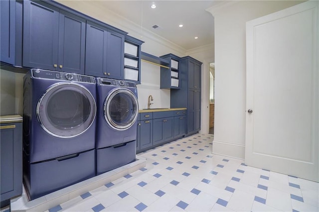 washroom featuring washing machine and dryer, sink, ornamental molding, cabinets, and light tile flooring