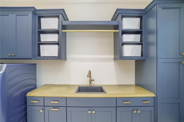 kitchen with blue cabinets, washer / clothes dryer, and sink