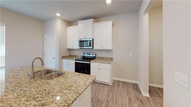 kitchen featuring light stone counters, light hardwood / wood-style flooring, white cabinets, appliances with stainless steel finishes, and sink