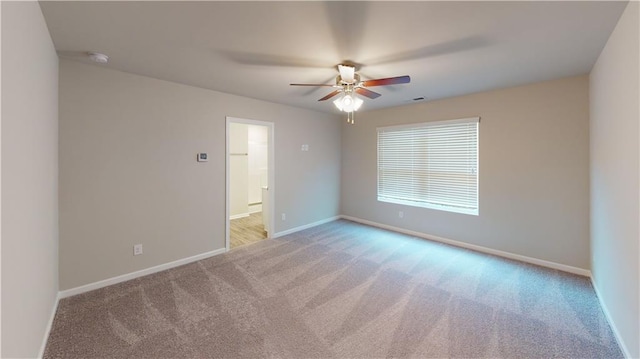 spare room with ceiling fan and light colored carpet