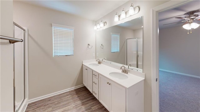 bathroom with a shower with door, ceiling fan, wood-type flooring, and vanity