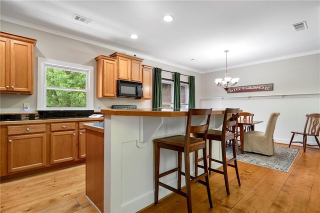 kitchen with a kitchen bar, light hardwood / wood-style floors, decorative light fixtures, a notable chandelier, and crown molding