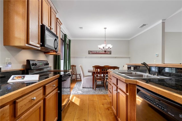 kitchen with decorative light fixtures, light wood-type flooring, a notable chandelier, black appliances, and sink