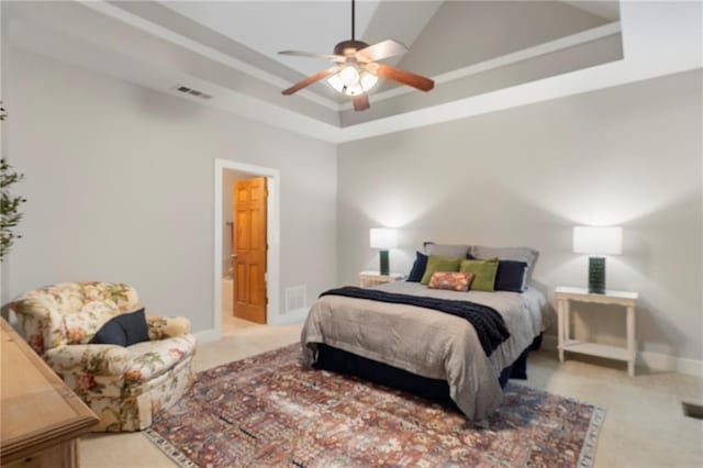 carpeted bedroom featuring ceiling fan, a raised ceiling, and ensuite bath