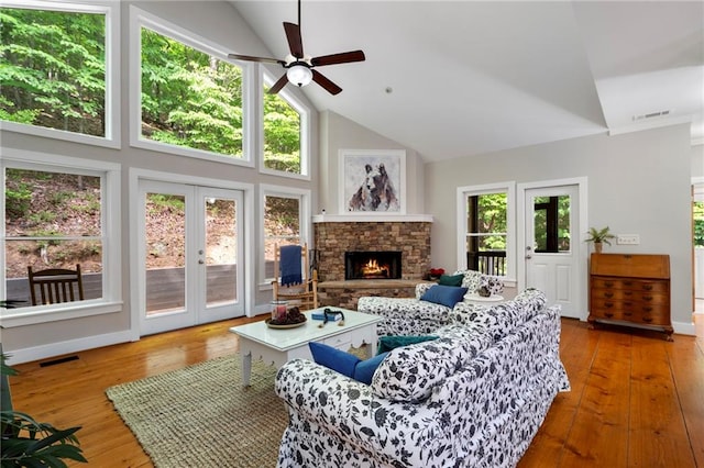 living room with ceiling fan, wood-type flooring, high vaulted ceiling, and a fireplace