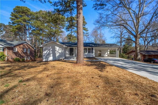 ranch-style home with a front lawn, an attached carport, and concrete driveway