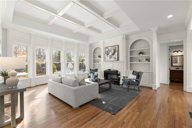 living room featuring beamed ceiling, built in shelves, coffered ceiling, and hardwood / wood-style floors