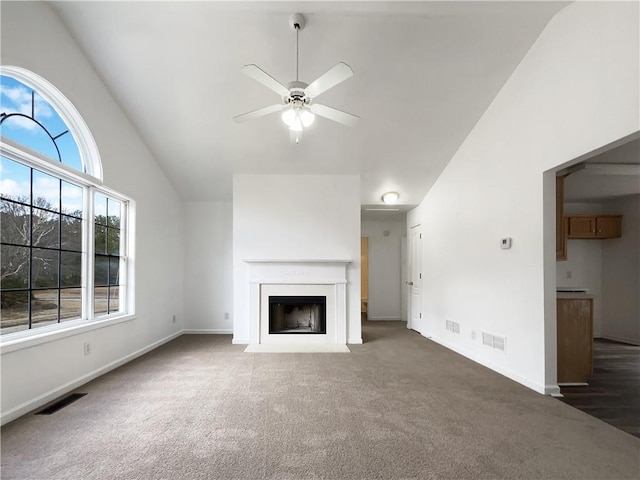 unfurnished living room featuring vaulted ceiling, dark carpet, and ceiling fan