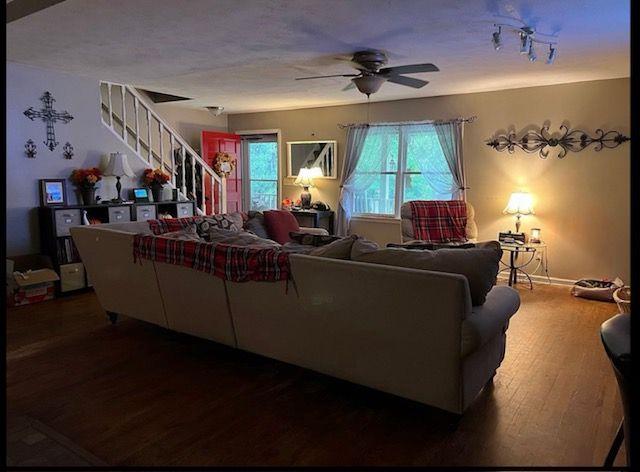 living room featuring dark wood-type flooring and ceiling fan