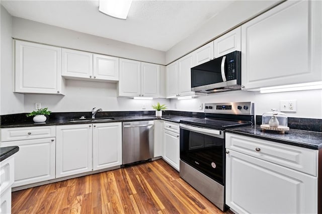 717 Beaufort Cir, Duluth, GA 30096 - kitchen featuring stainless steel appliances, a sink, white cabinetry, and wood finished floors