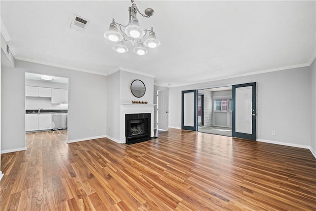 717 Beaufort Cir, Duluth, GA 30096 - unfurnished living room featuring ornamental molding, baseboards, wood finished floors, a chandelier, and a sink