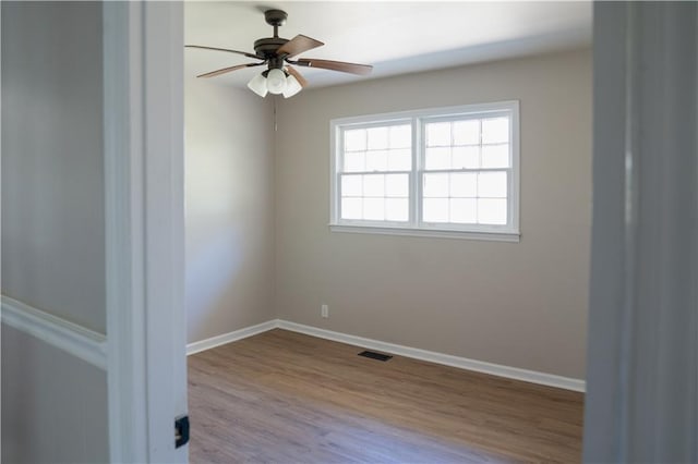 spare room featuring visible vents, ceiling fan, baseboards, and wood finished floors