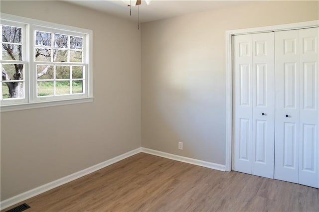 unfurnished bedroom with visible vents, light wood-style flooring, baseboards, and a closet