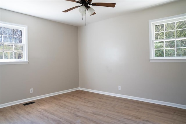 spare room featuring visible vents, a ceiling fan, baseboards, and wood finished floors