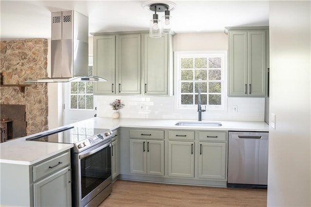 kitchen featuring decorative backsplash, a peninsula, island exhaust hood, stainless steel appliances, and a sink