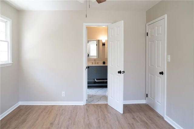 unfurnished bedroom with wood finished floors, baseboards, and a sink