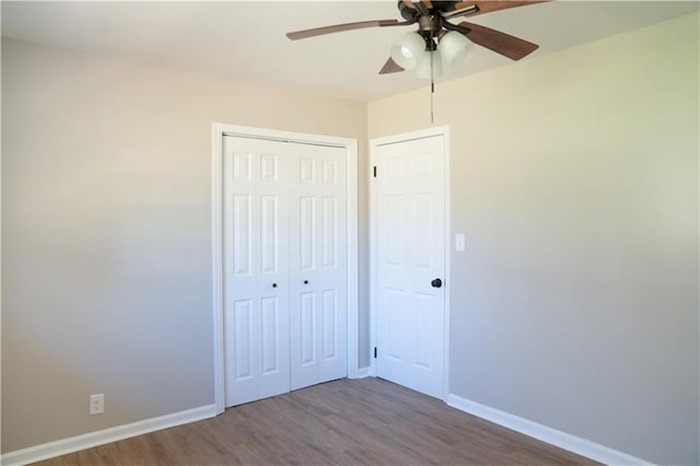 unfurnished bedroom featuring wood finished floors, baseboards, and a closet