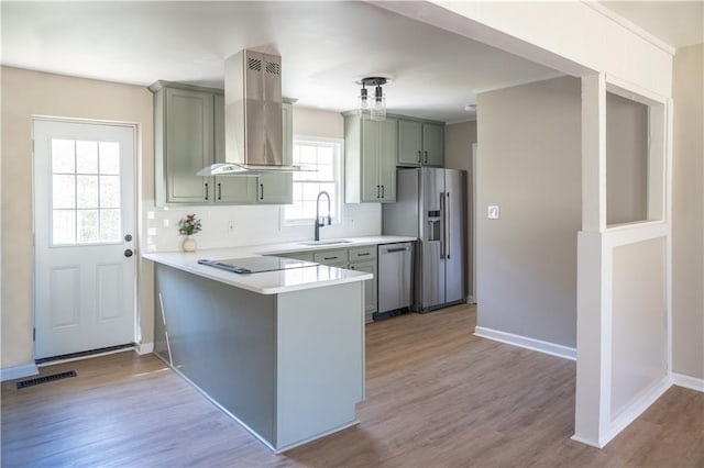 kitchen featuring visible vents, island exhaust hood, a sink, appliances with stainless steel finishes, and light countertops