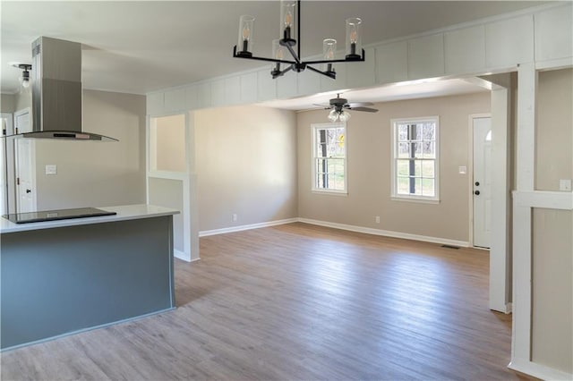 unfurnished living room featuring visible vents, ceiling fan with notable chandelier, light wood-type flooring, and baseboards